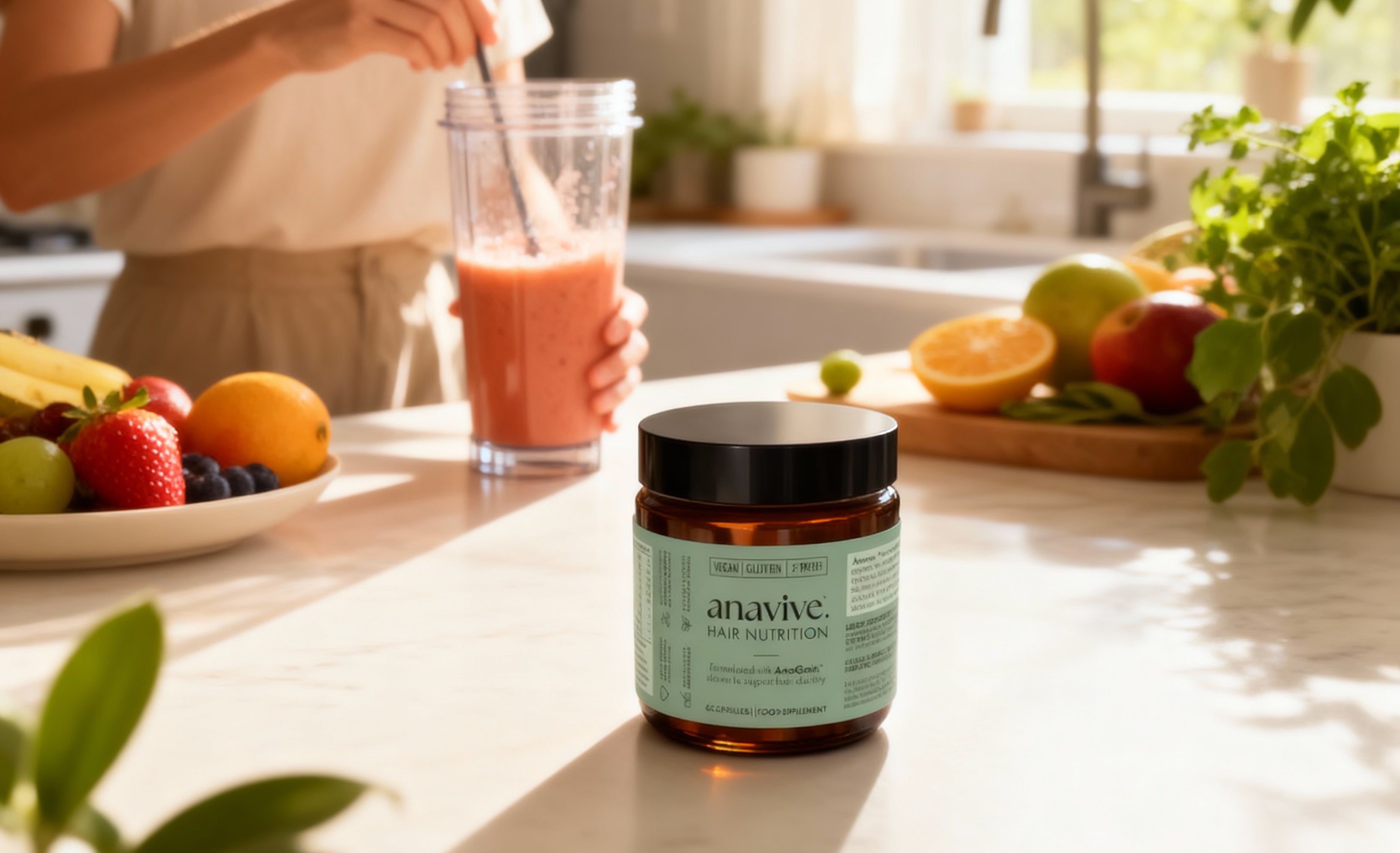 Jar of anavive hair nutrition supplement on a kitchen counter with a smoothie and fruits in the background.